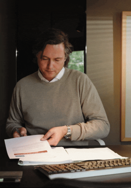 man zit aan bureau met papieren